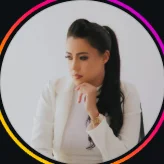 Ana Flávia Araújo, de blazer claro, apoiando o queixo na mão