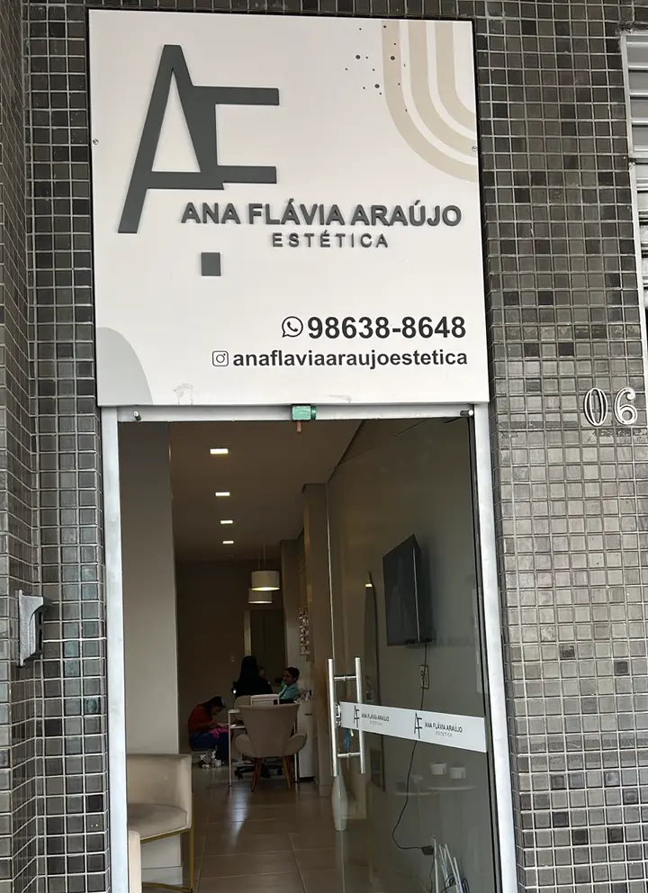 Fachada da Ana Flávia Araújo Estética: placa clara com o monograma AF e a porta de vidro aberta para a recepção