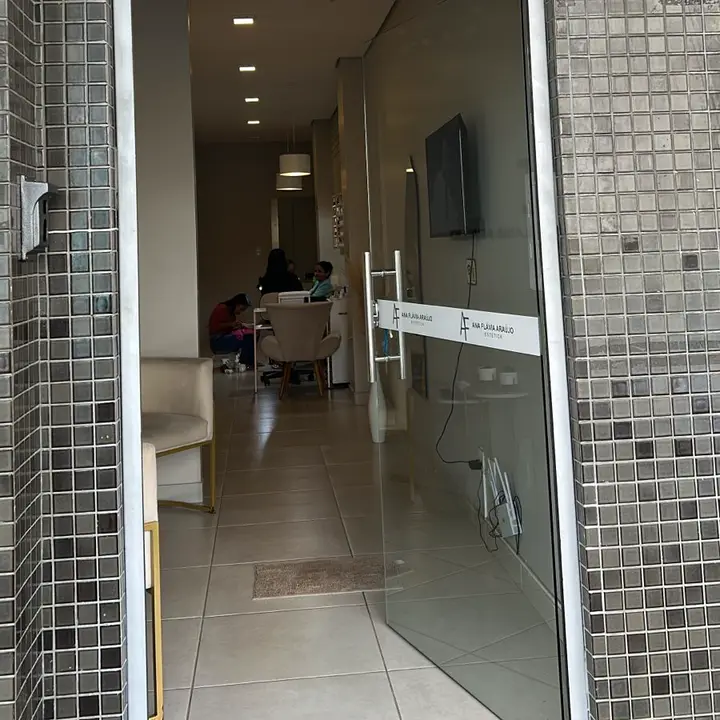 Porta de vidro do estúdio com o nome Ana Flávia Araújo e a recepção ao fundo